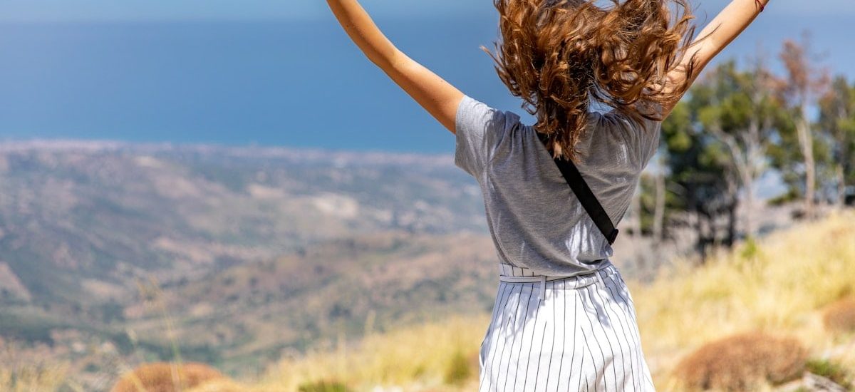 a woman with her hair in the air on top of a hill