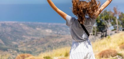 a woman with her hair in the air on top of a hill