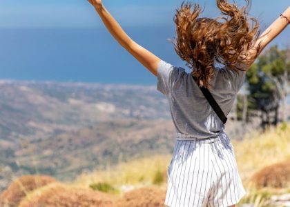 a woman with her hair in the air on top of a hill